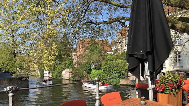 Een restaurant aan de rivier met terras, uitzicht op het water en een passerend schip.