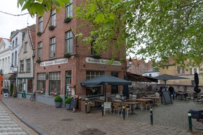 Een geplaveid straatje met terrasjes van een restaurant genaamd 'Hotel Restaurant Wilenspiegel' en 'Brasserie Resthouse Hotel'.