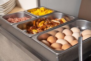 Een buffet met diverse gerechten, waaronder eieren, worst en aardappelen.
