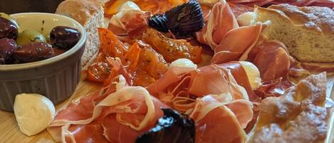 A charcuterie board with various meats, cheeses, and olives.