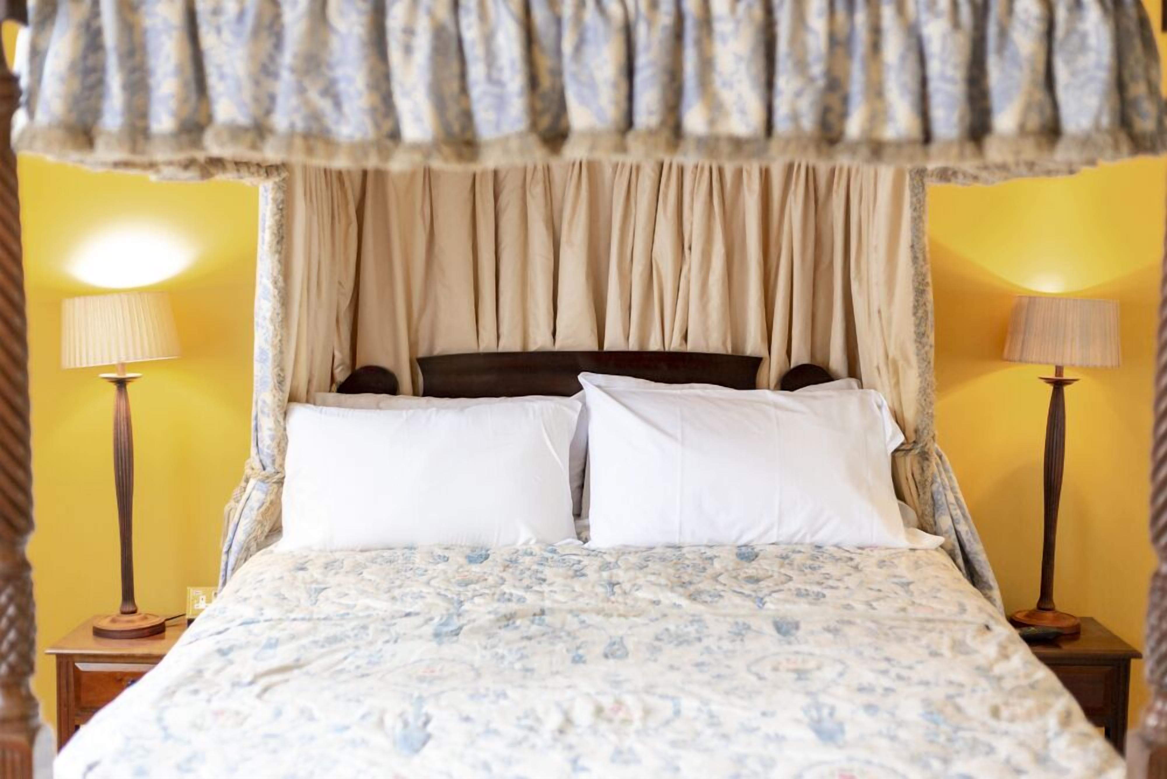 A bed with a canopy, two bedside lamps, and a floral bedspread.