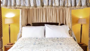 A bed with a canopy, two bedside lamps, and a floral bedspread.