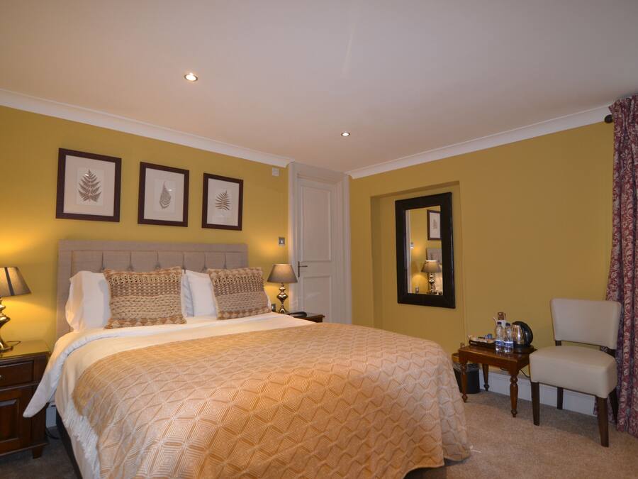 A hotel room with a large bed, two bedside tables with lamps, a chair, and framed artwork on the wall.