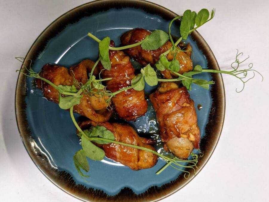 Un plato de alitas de pollo glaseadas, adornadas con brotes tiernos.