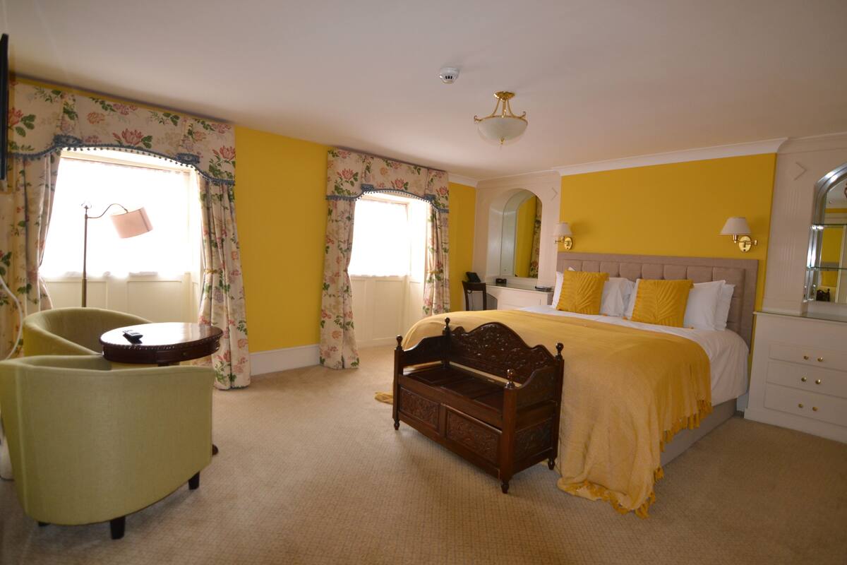 A bedroom with a bed, a chair, a bedside table, and a lamp.