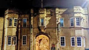 A historic building with a central entrance, multiple windows, and a sign indicating a car park. - Angel & Royal Hotel (Grantham)