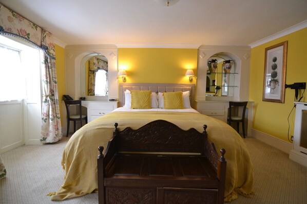A bedroom with a large bed, two bedside tables, a nightstand, a mirror, and a window with curtains. - Angel & Royal Hotel (Grantham)