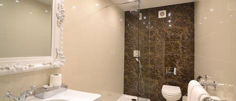 A modern bathroom with a marble wall, a sink, a toilet, and a shower.
