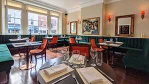 A restaurant with green booths, wooden tables, and red chairs. - Angel & Royal Hotel (Grantham)