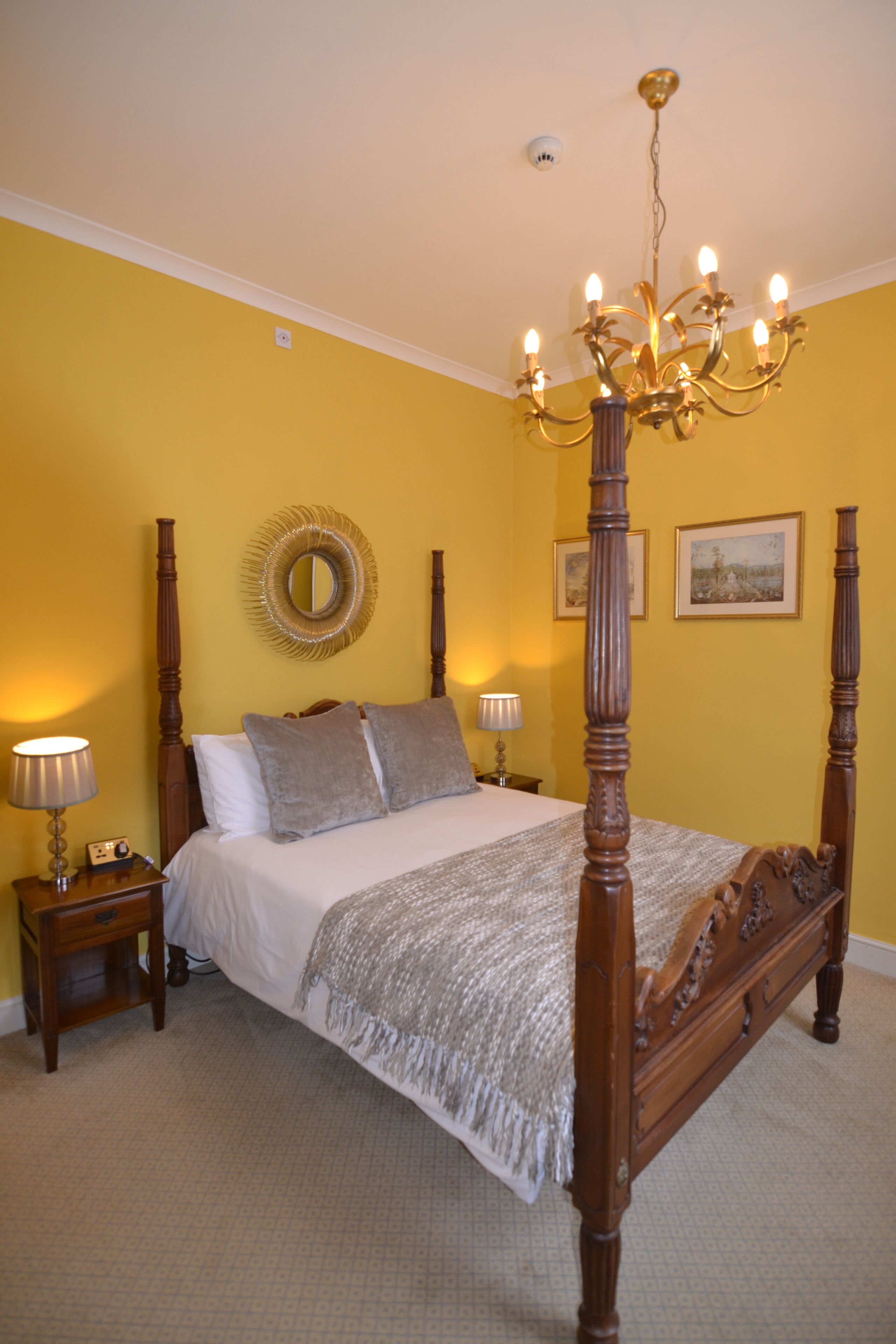 Uma cama de dossel com estrutura de madeira e um espelho decorativo acima.