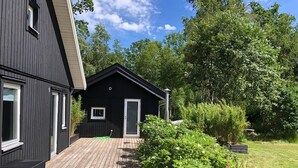 A modern black house with a wooden deck and a small garden area.