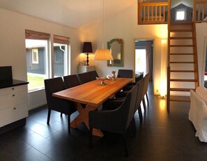 A dining area with a wooden table and chairs, a lamp, and a mirror on the wall.
