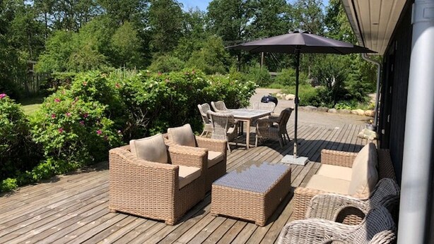 An outdoor patio with wicker furniture, a table, and an umbrella.