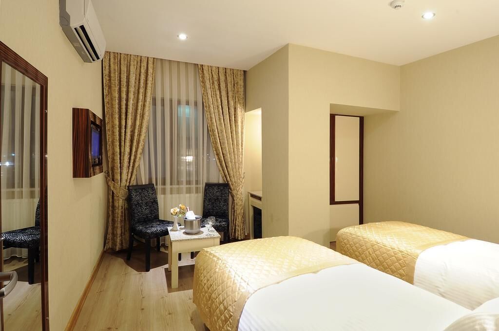 A hotel room with two beds, a desk, a chair, a TV, and a mirror.
