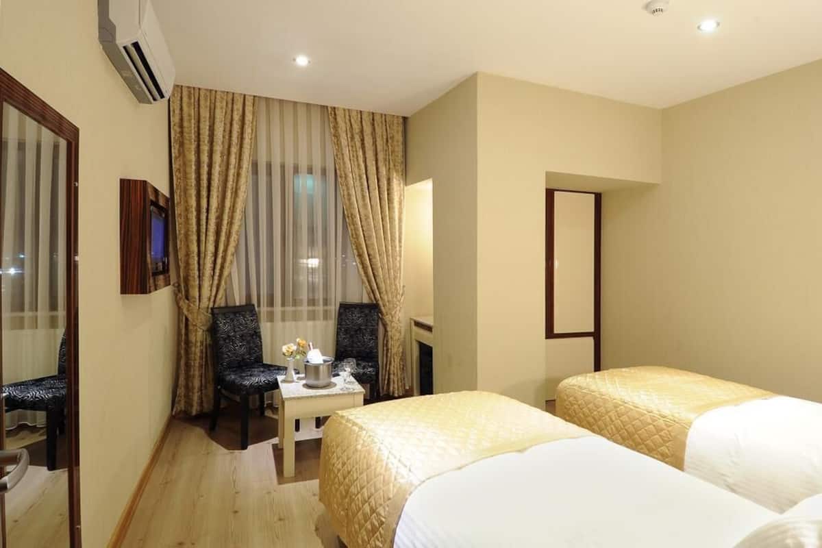 A hotel room with two beds, a desk, a chair, a TV, and a mirror.