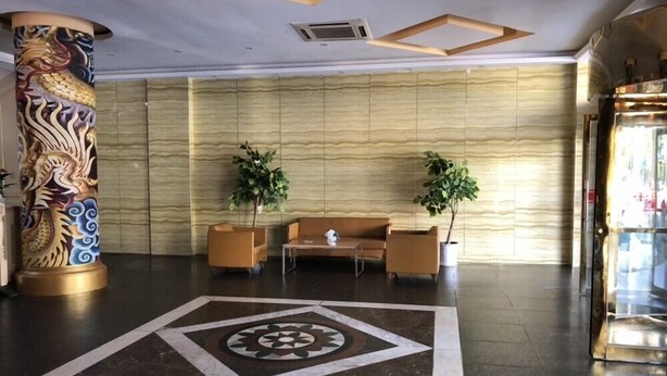 Un vestíbulo con una columna decorativa, dos sofás, una mesita de centro y un diseño de suelo estampado.