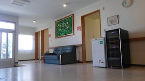 Une salle d’attente avec un canapé bleu, un réfrigérateur et une horloge au mur.