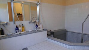 Une salle de bain équipée d’une douche, d’une baignoire et d’un lavabo, avec de nombreux flacons de produits de toilette.