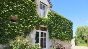 A building with a white door and windows, covered partially by green ivy. - Roulotte à la Ferme de l'Isle (Avaray)