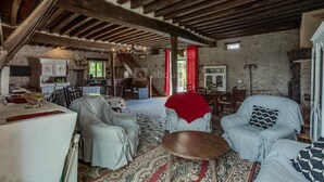 A rustic interior with exposed wooden beams, a dining area, and a cozy seating arrangement. - Roulotte à la Ferme de l'Isle (Avaray)