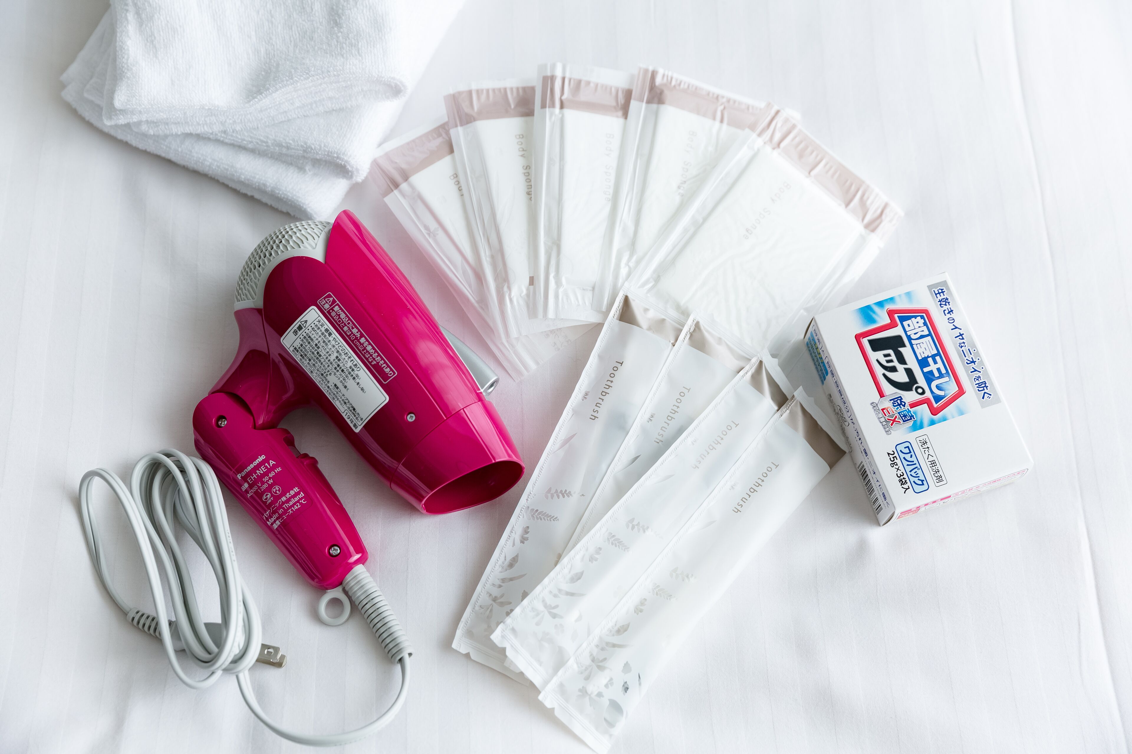 A hair dryer, several hair clips, and a box of hair ties on a white surface.