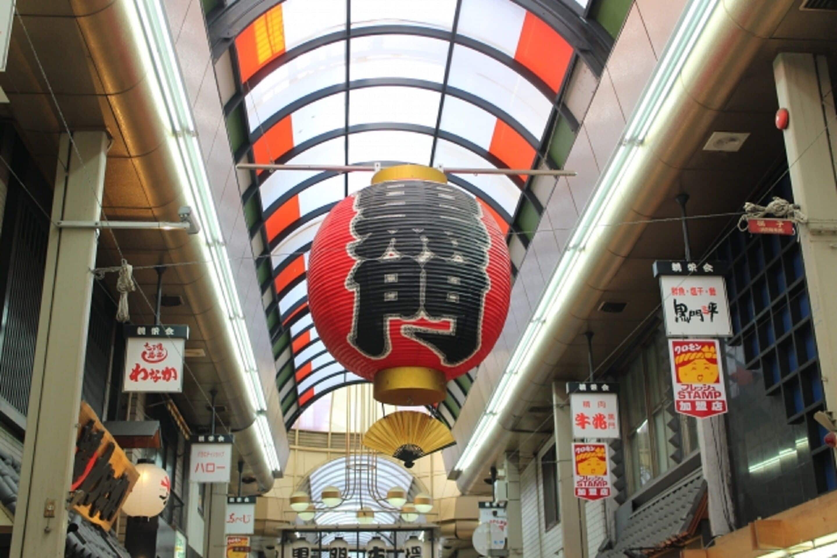 A corridor with a curved ceiling, hanging lanterns, and signs with Japanese characters.