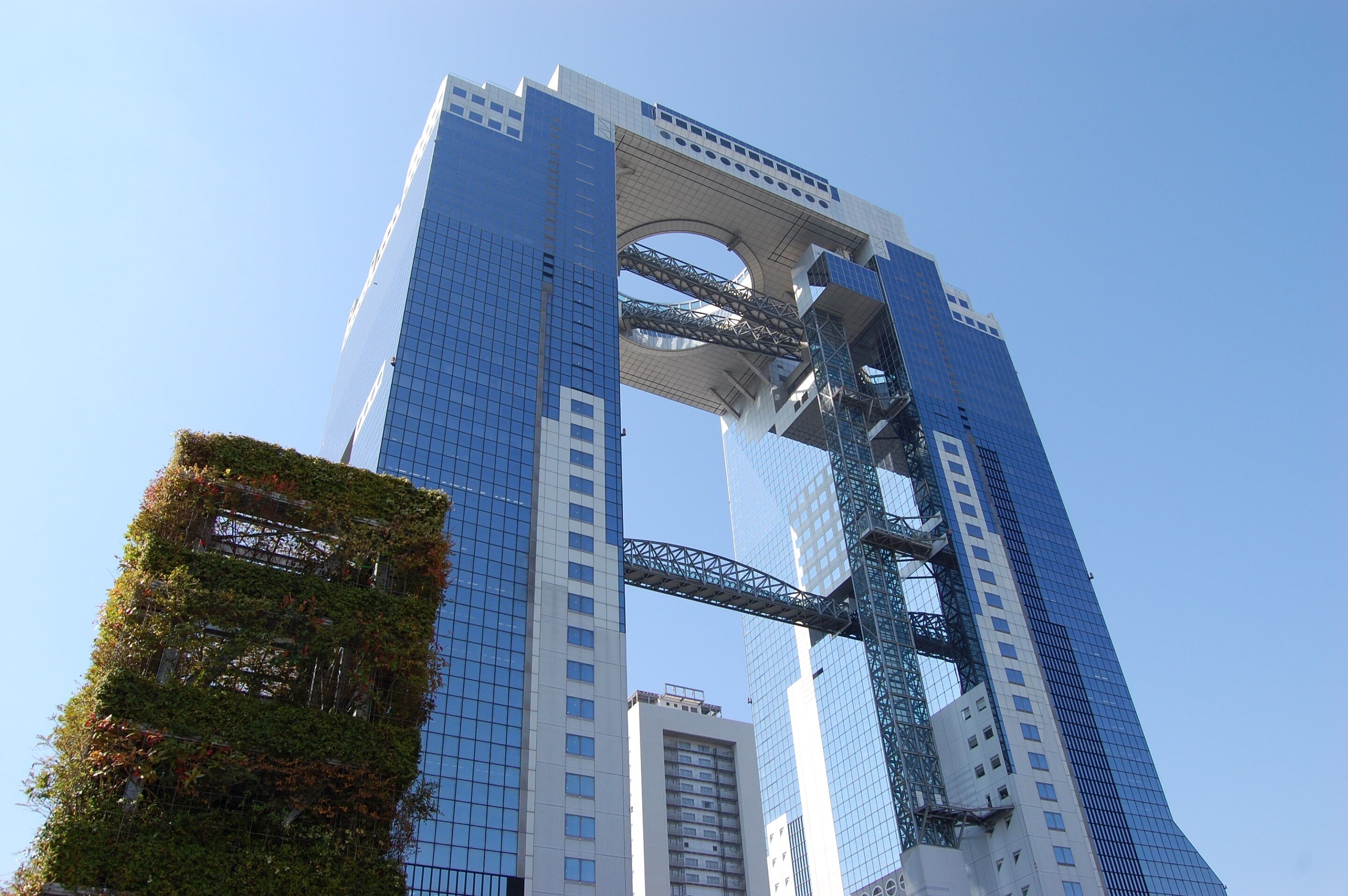 A tall building with a distinctive arched structure at the top, surrounded by other high-rise buildings.