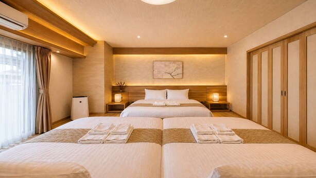 A hotel room with two beds, a wooden ceiling, a wall-mounted artwork, and a bedside table with a lamp. - Takuto Stay Sakaisuji-Honmachi (Osaka)