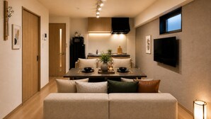 A modern interior with a sofa, dining table, and kitchen area. - Takuto Stay Sakaisuji-Honmachi (Osaka)