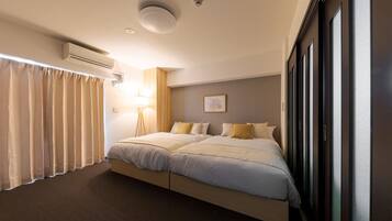A hotel room with a large bed, a bedside table, a lamp, and a window with curtains.