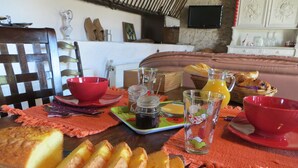 A breakfast table with bread, a jug of orange juice, and a red bowl. - Chambres d'hotes Domaine de l'Isle (Avaray)