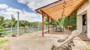A covered outdoor area with a wooden deck, lounge chairs, and a table. - Chambres d'hotes Domaine de l'Isle (Avaray)