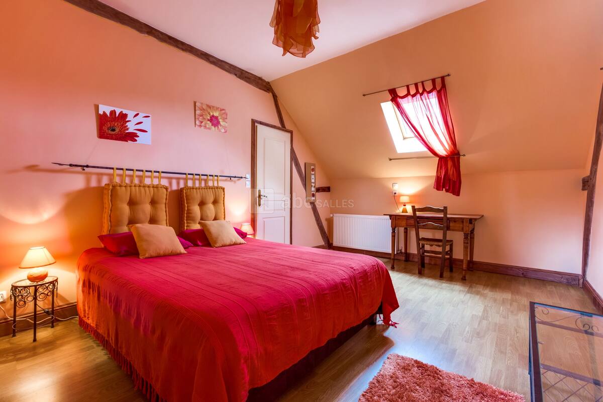 Une chambre à coucher avec un grand lit, un bureau et une fenêtre avec des rideaux.