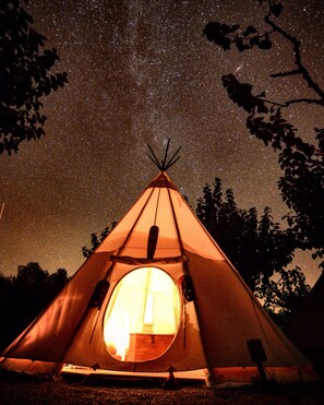 A teepee with a circular entrance and a starry night sky visible through the opening. - Camping El Roble (Valderrobres)