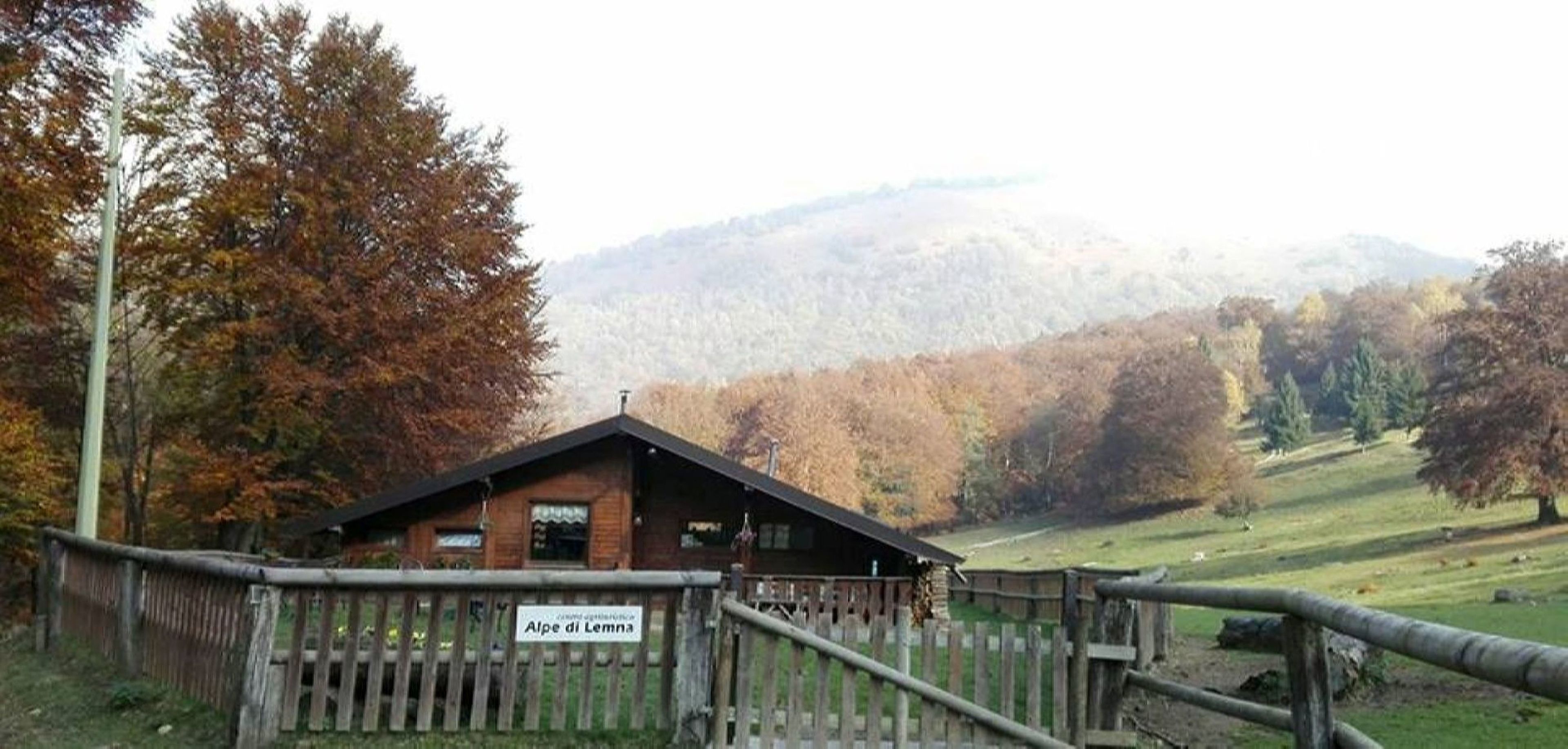Un rifugio rustico con una recinzione di legno e un cartello che riporta la scritta 'Alpe di Lemna'.