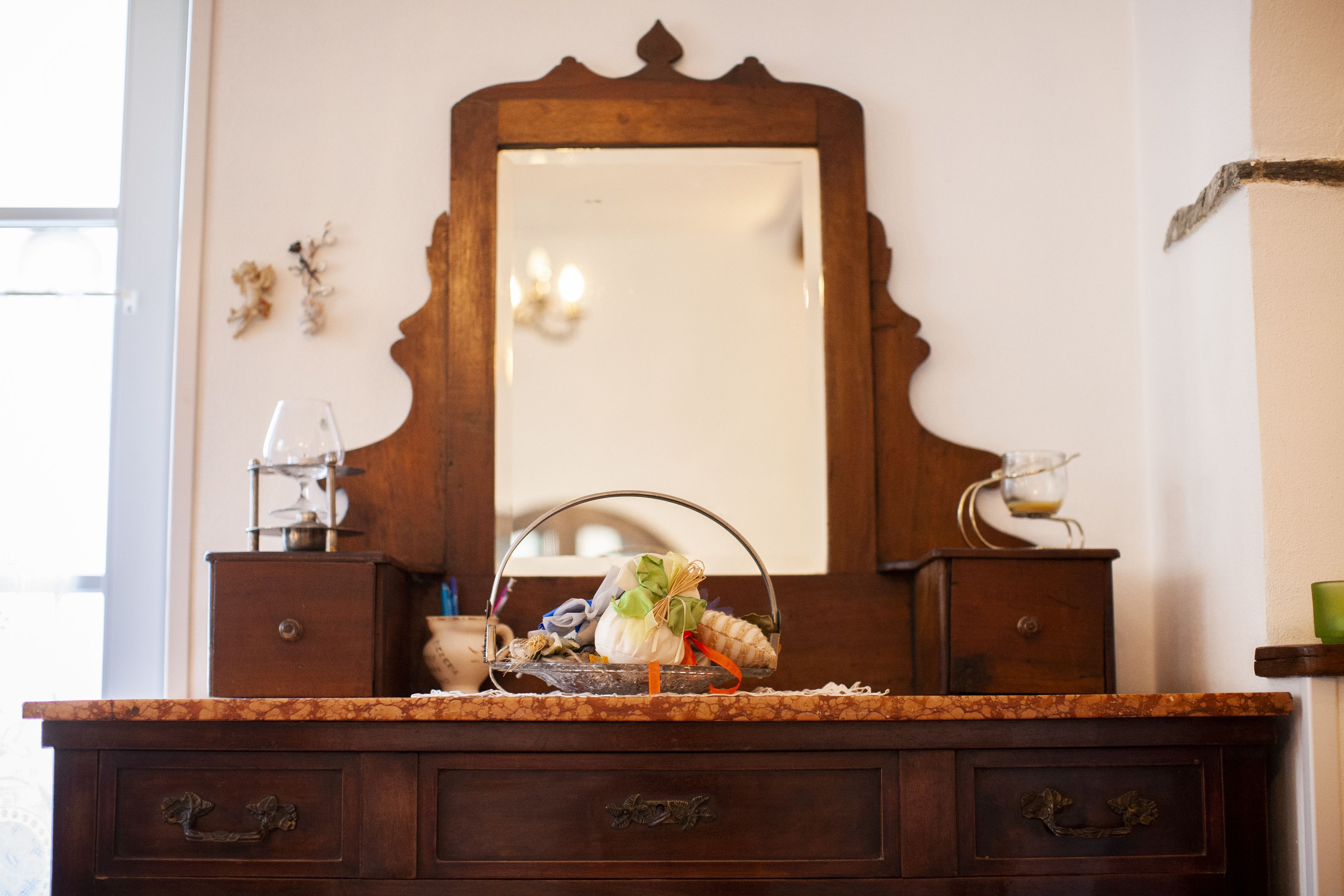 A wooden dresser with a mirror above it, drawers, and a countertop with a glass and a basket.