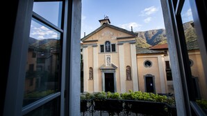 A building with a central entrance, a cross on top, and a surrounding fence. - Antica Molina (Faggeto Lario)