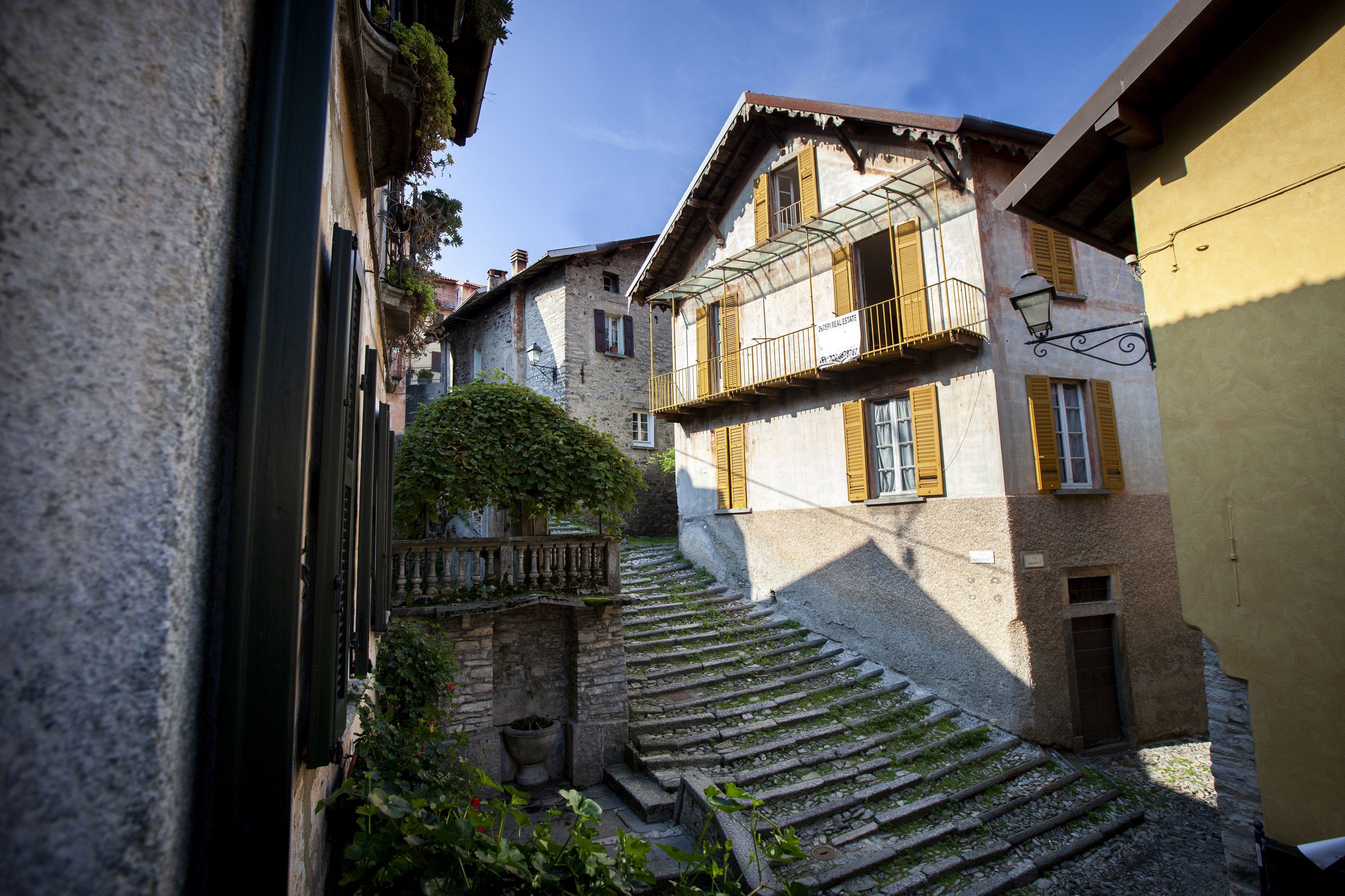 A narrow street with stone steps leading to a building with a balcony.