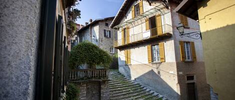 A narrow street with stone steps leading to a building with a balcony.