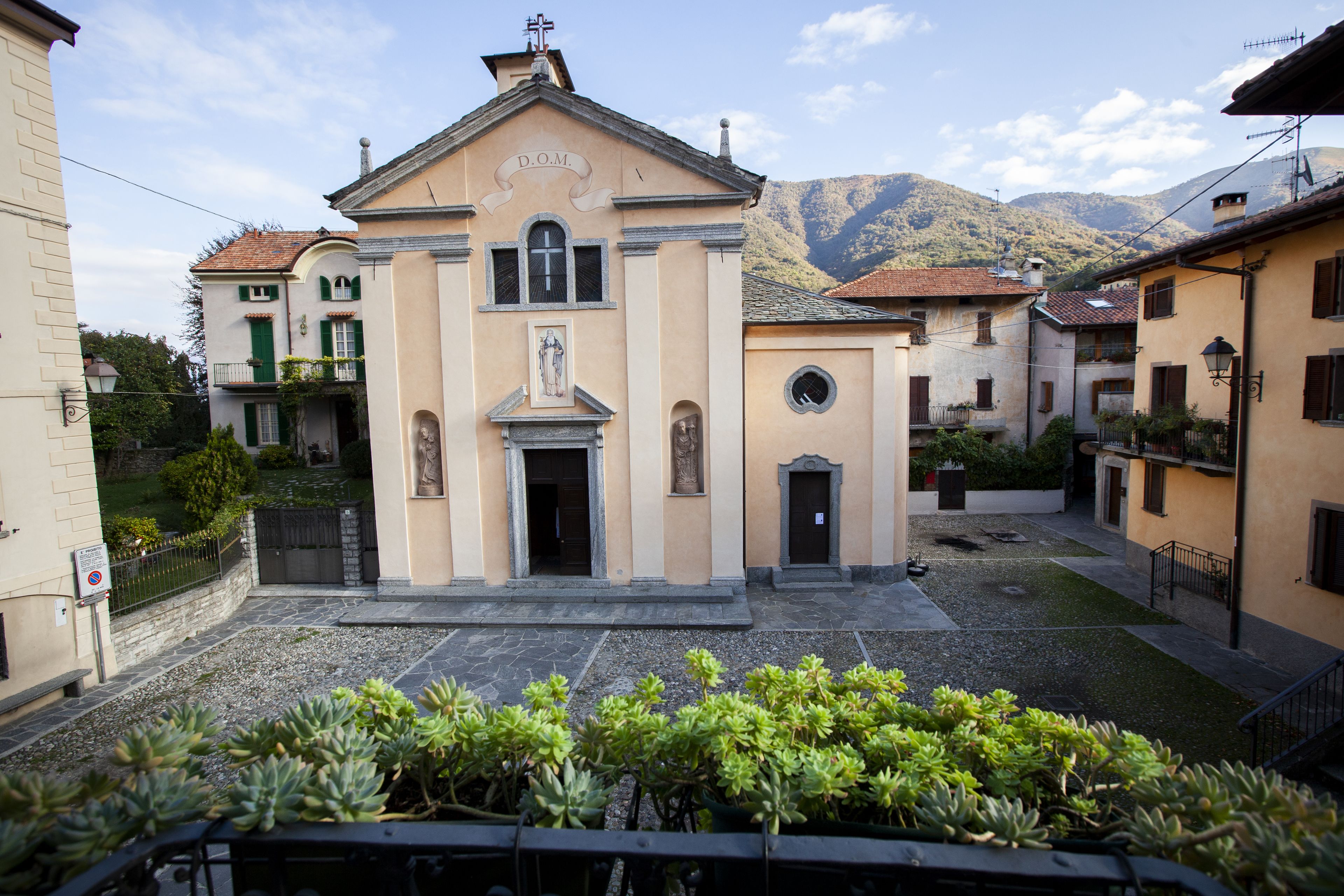 Un edificio con un cartello che riporta la scritta "D.O.M." sullo sfondo di una montagna.