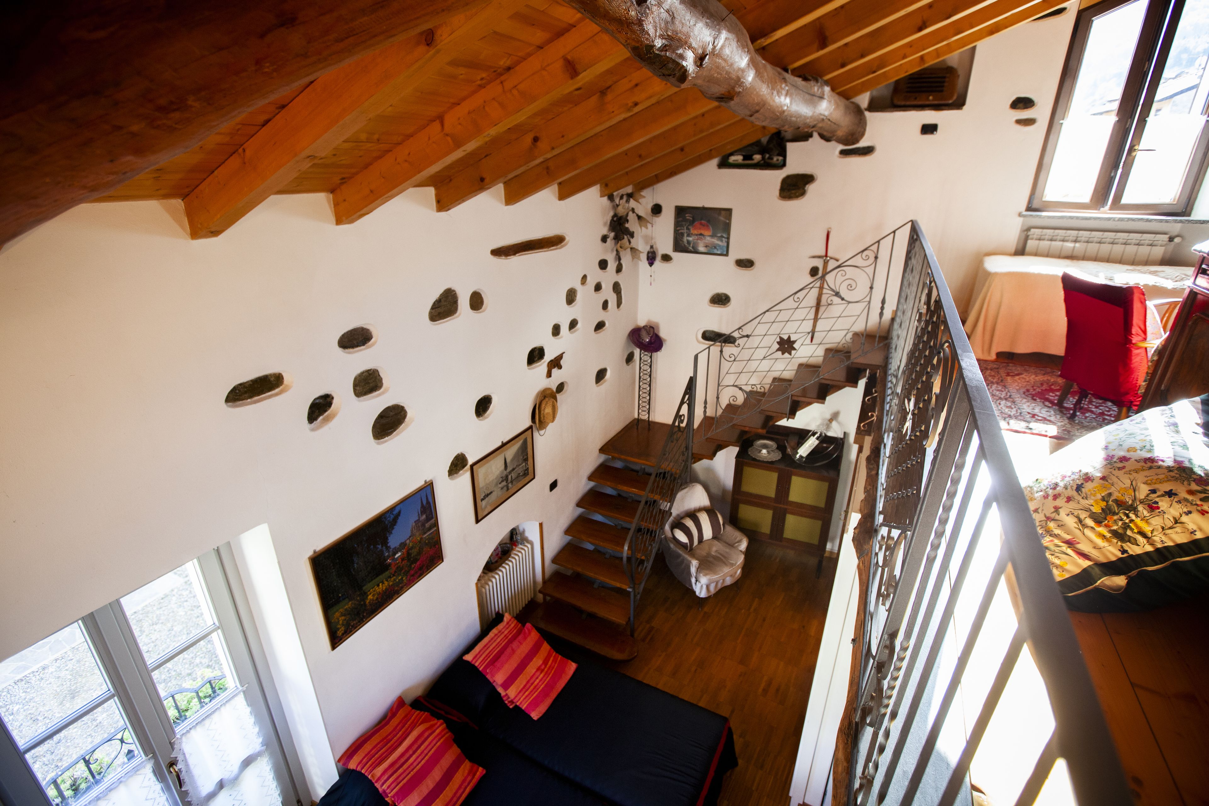 Una habitación con techo de madera, una escalera, una cama y un ventanal.