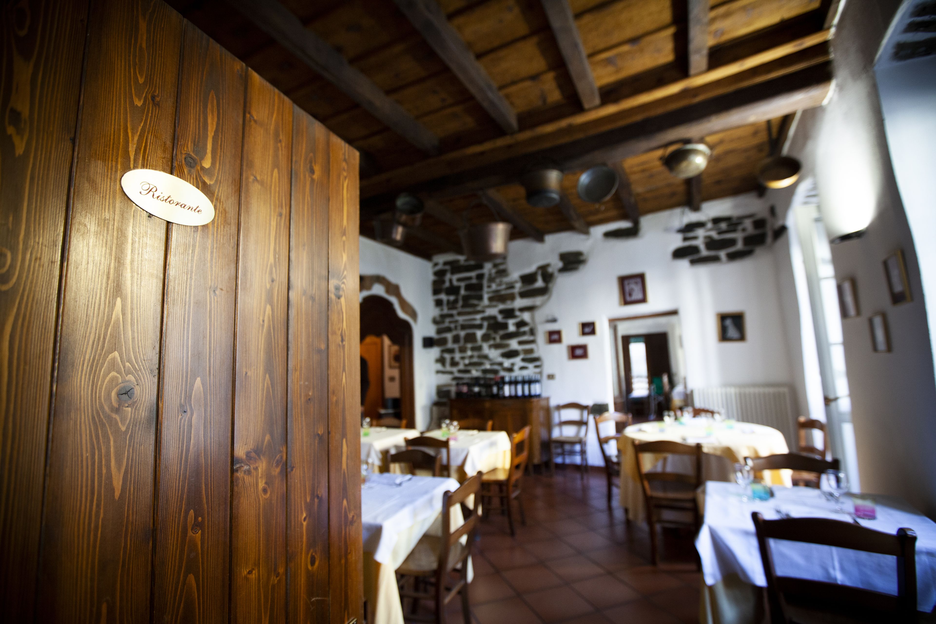 A restaurant interior with wooden walls, stone accents, and tables set for dining.