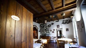 A restaurant interior with wooden walls, stone accents, and tables set for dining.