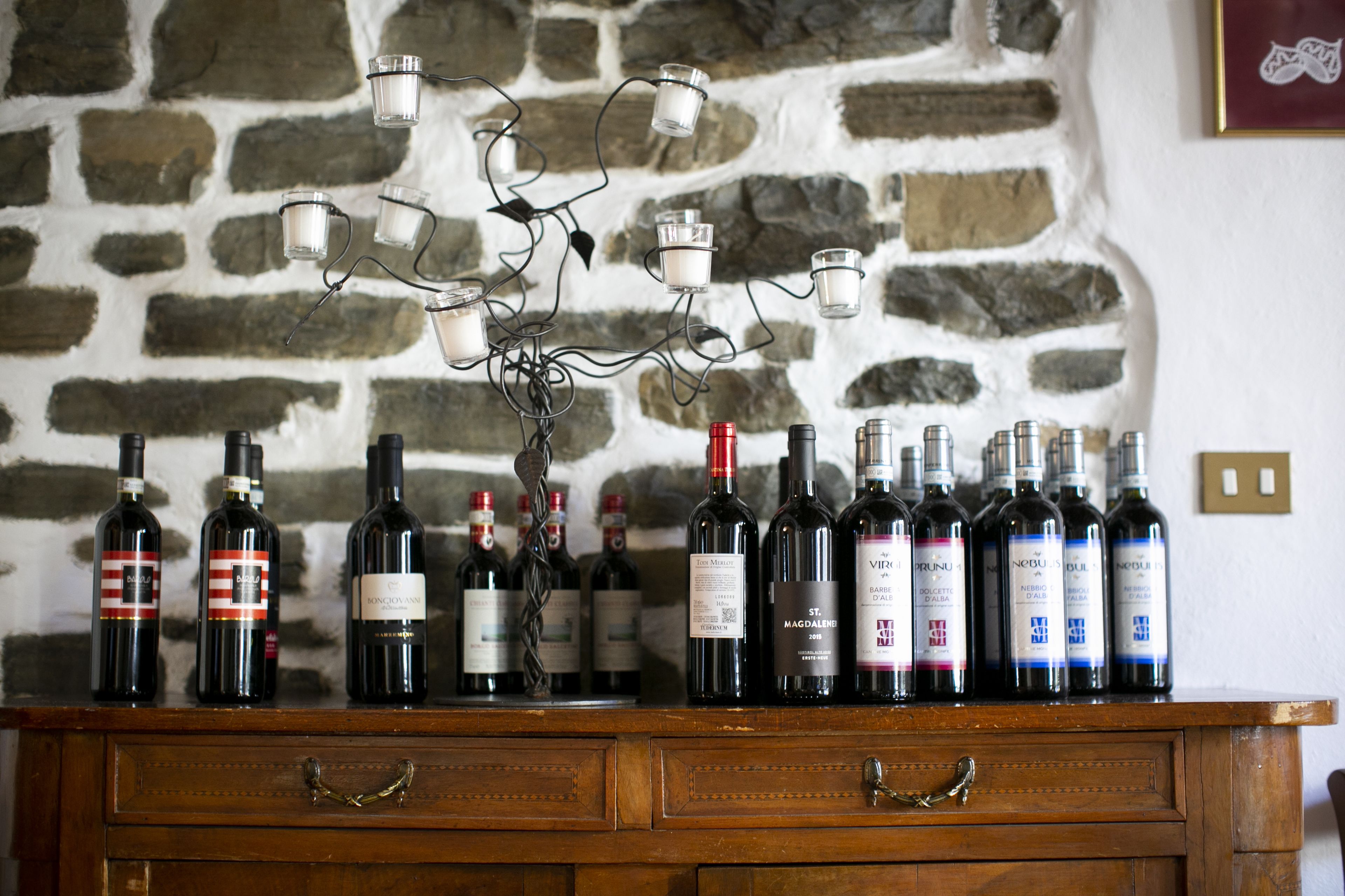 A wooden wine rack with bottles of wine against a stone wall.