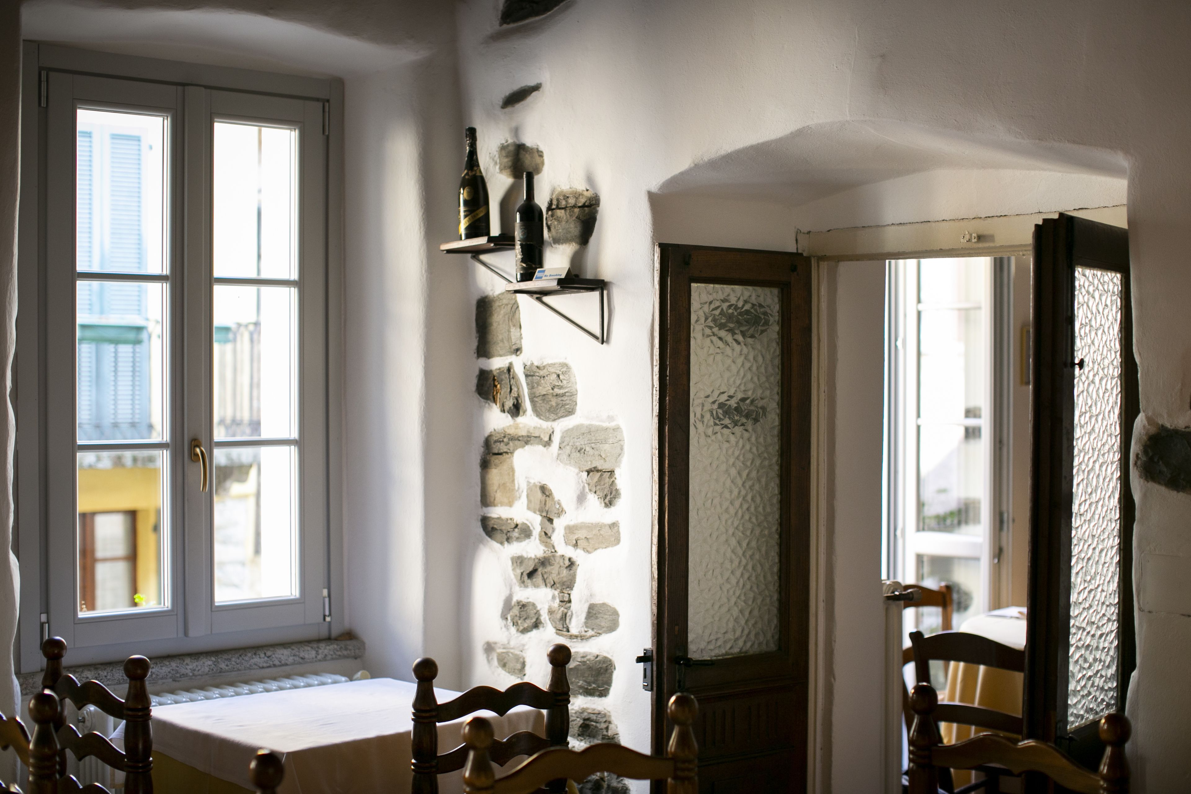 A room with a stone wall, a wooden bench, and a door leading to another room.