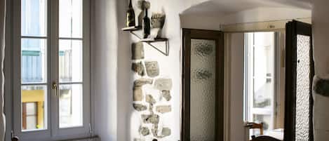 A room with a stone wall, a wooden bench, and a door leading to another room.