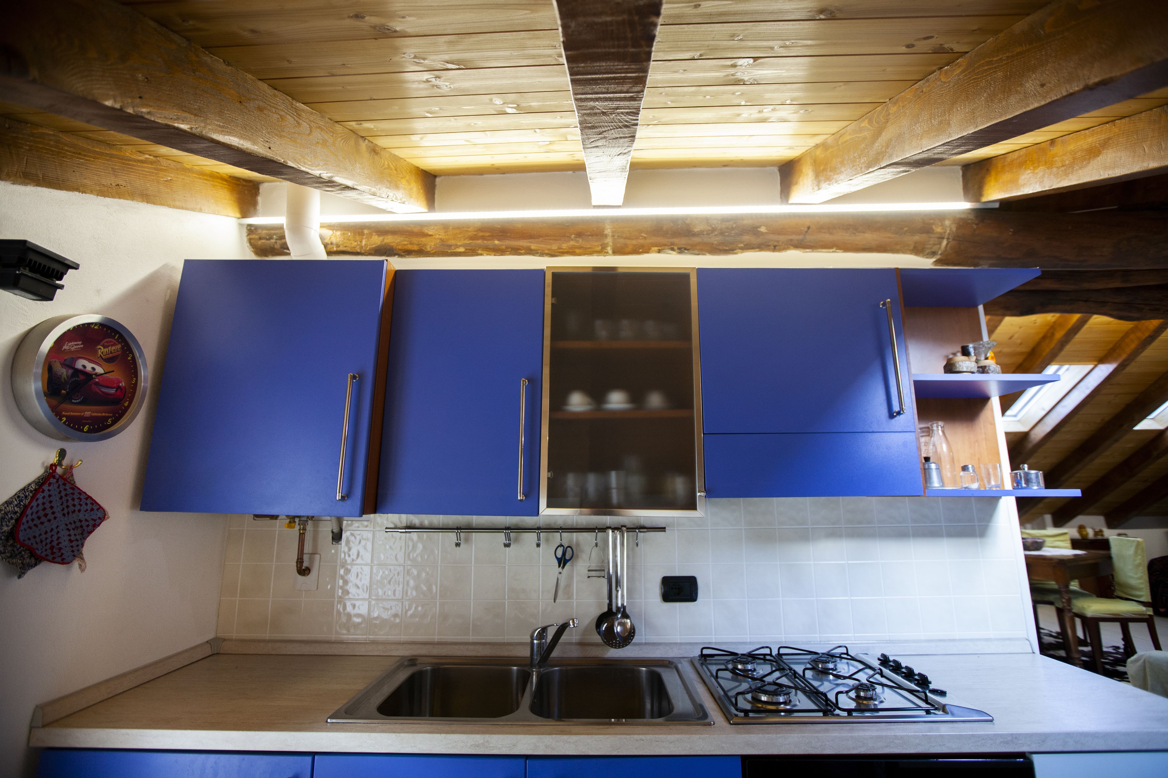 Une cuisine avec des meubles de couleur bleue, un évier à deux bacs et une cuisinière à gaz.
