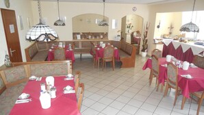Ein Restaurant mit Sitzgelegenheiten in Form von Boxen und Tischen, alle mit roten Tischdecken bedeckt.