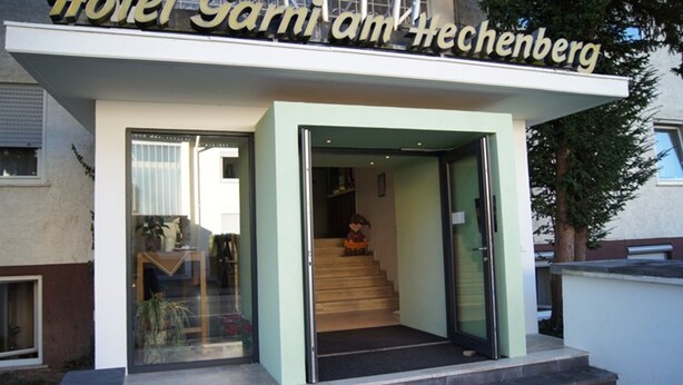 Ein Hotel Eingang mit Glastür, einer sichtbaren Innentreppe und einem Schild über der Tür.