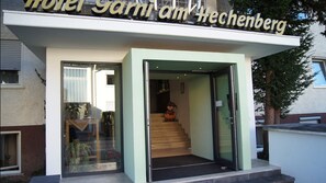 A hotel entrance with a glass door, a visible staircase leading inside, and a sign above the entrance.